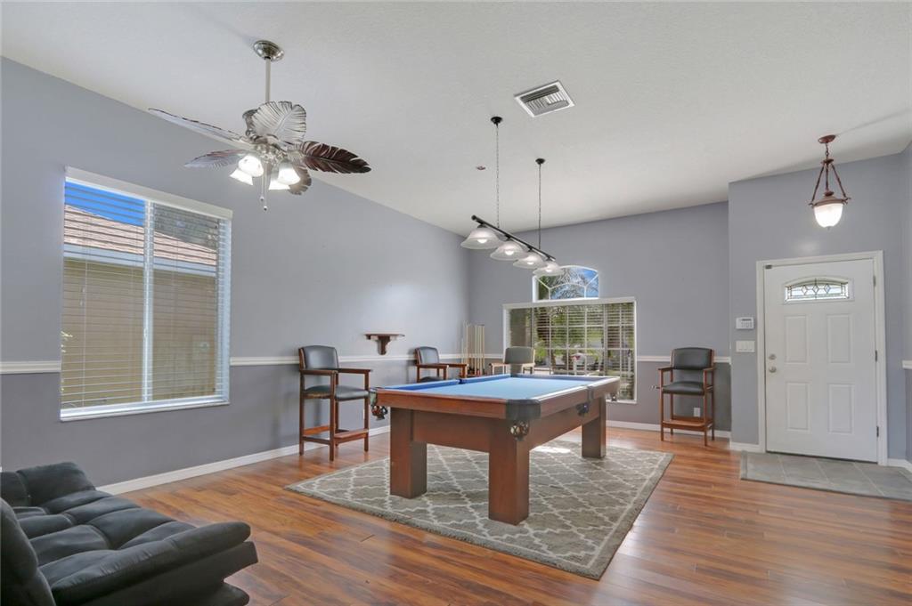 2539 Southeast Springtree Place Stuart, FL 34997 - Photo 4 of 20 a dining room with wooden floor a chandelier a wooden table and chairs