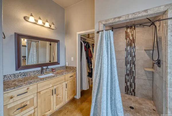 a bathroom with a granite countertop shower a sink and a mirror
