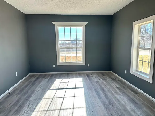 an empty room with wooden floor and windows