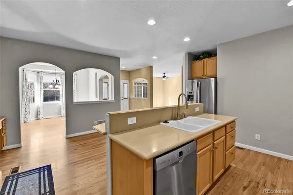 a kitchen with a stove a sink a refrigerator and a dining table with wooden floor