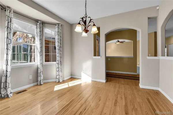an empty room with wooden floor mirror and windows