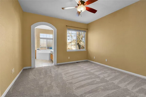 an empty room with windows and fan