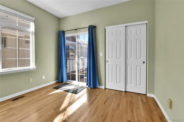 an empty room with wooden floor and windows