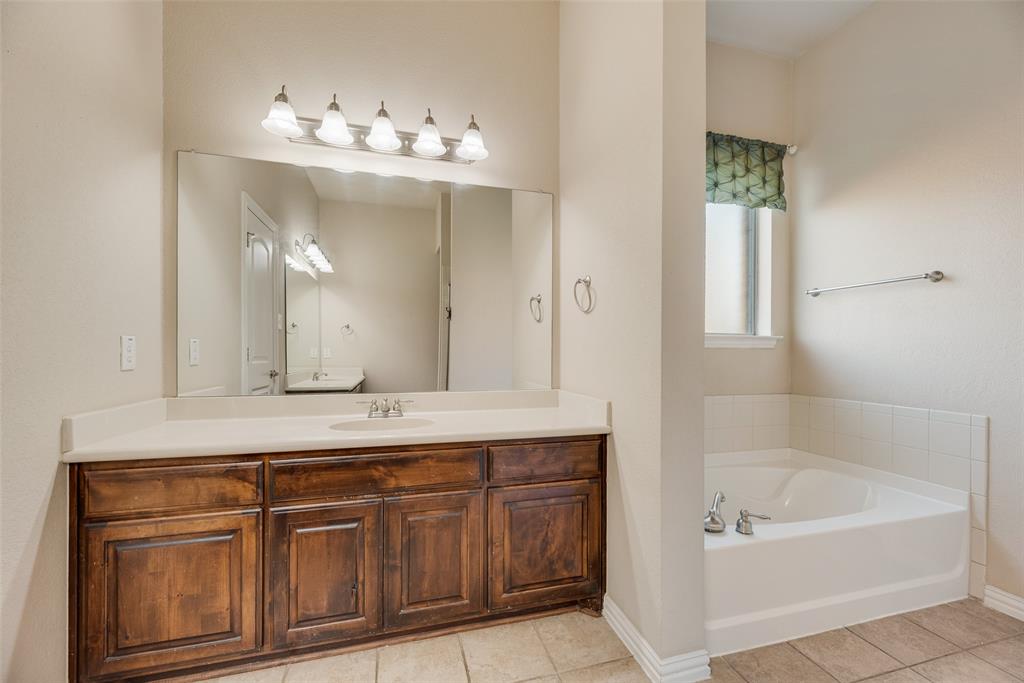 1010 Newington Circle Forney, TX 75126 - Photo 14 of 26 a bathroom with a tub a double vanity sink and a mirror