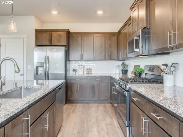 a kitchen with stainless steel appliances granite countertop a sink a stove and a refrigerator