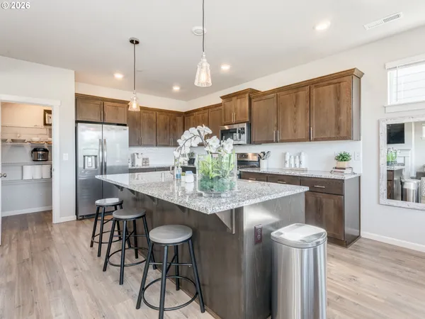 a kitchen with stainless steel appliances granite countertop a stove refrigerator and cabinets with wooden floor