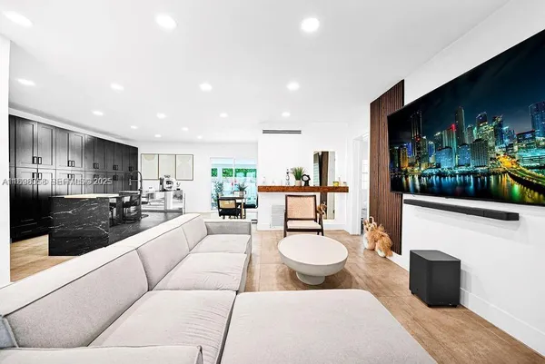 a living room with stainless steel appliances furniture a rug and a kitchen view