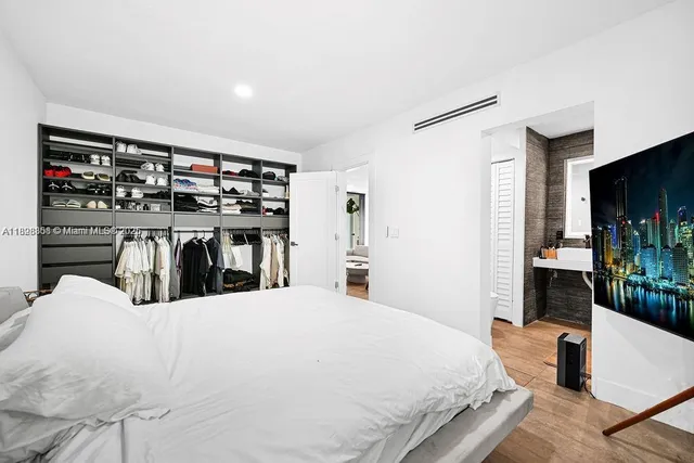 a bedroom with a large bed and a flat tv screen on dresser