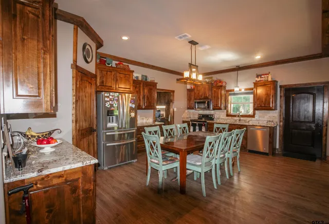 a kitchen with stainless steel appliances a dining table chairs stove and refrigerator