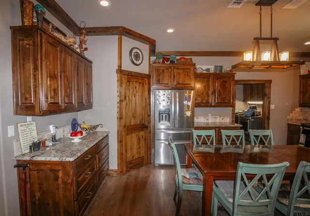 a kitchen with granite countertop lots of wooden furniture and stainless steel appliances