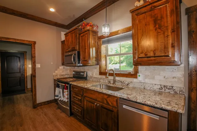 a kitchen with stainless steel appliances granite countertop a sink stove and cabinets