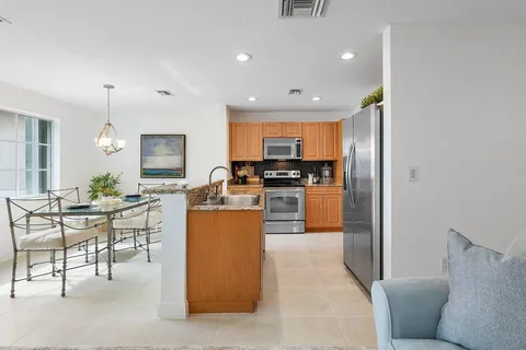 a kitchen with stainless steel appliances kitchen island granite countertop a refrigerator a stove a sink a dining table and chairs