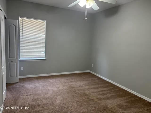 an empty room with a chandelier fan and windows