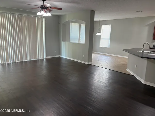 an empty room with wooden floor cabinet and windows