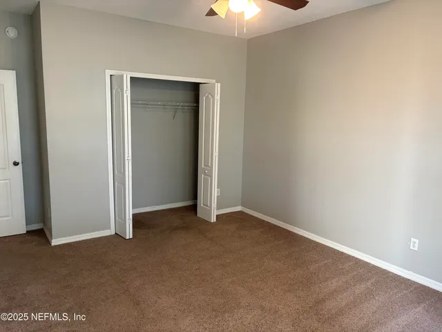 an empty room with a ceiling fan and a window