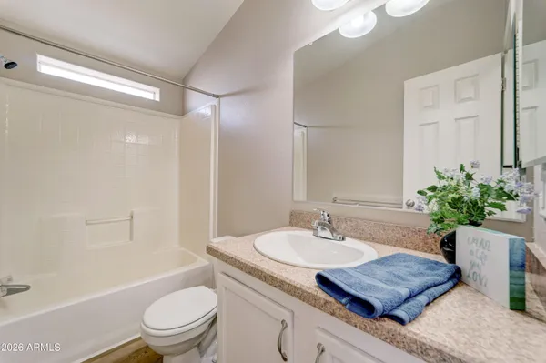 a bathroom with a granite countertop sink a toilet a mirror a bathtub and shower