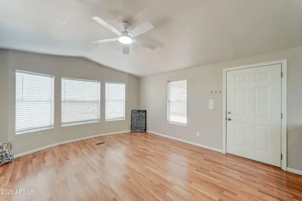 an empty room with wooden floor fan and windows