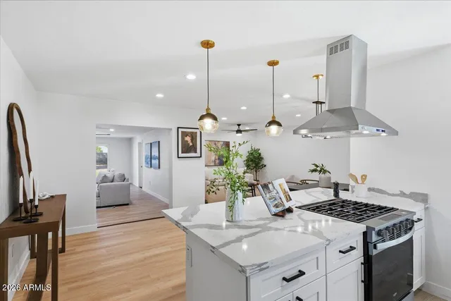 a large kitchen with kitchen island a stove a sink a center island and wooden floor