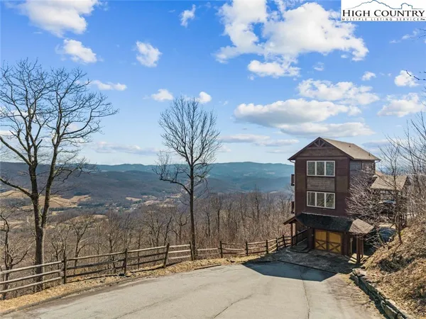 a view of a brick house next to a yard with large trees