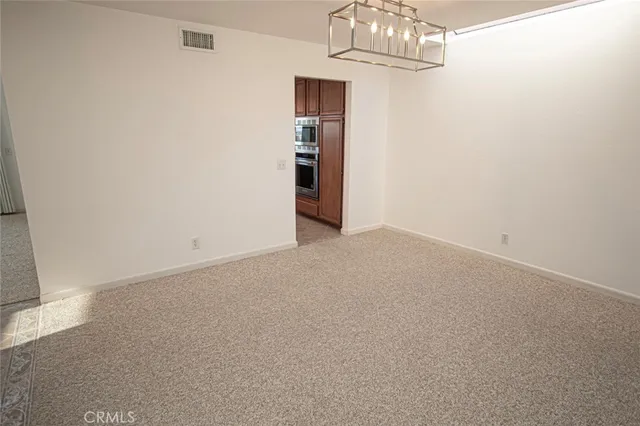 an empty room with a chandelier fan and wooden floor