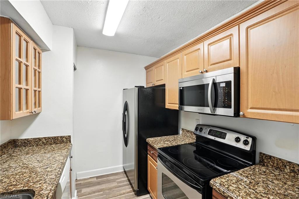 201-5 Santa Clara Drive, Unit 201 Naples, FL 34104 - Photo 5 of 23 a kitchen with stainless steel appliances granite countertop a refrigerator and a stove top oven