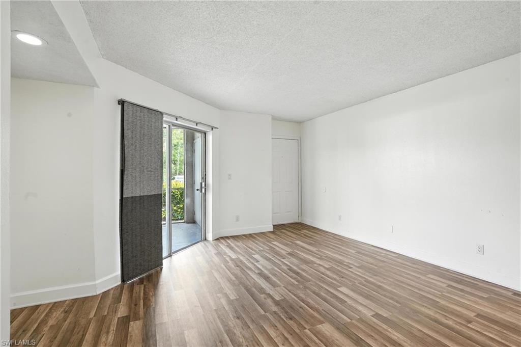 201-5 Santa Clara Drive, Unit 201 Naples, FL 34104 - Photo 9 of 23 an empty room with wooden floor and windows