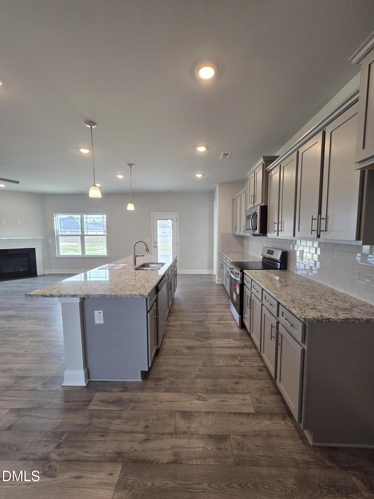 4979 Trident Maple Court Battleboro, NC 27809 - Photo 21 of 41 a large kitchen with stainless steel appliances kitchen island granite countertop a large counter top and view of living room