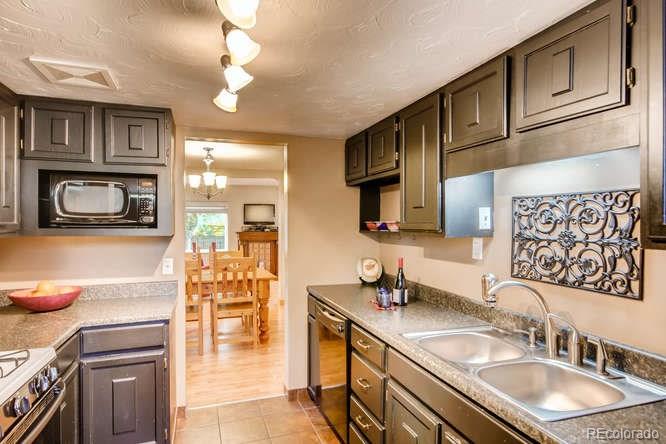 2917 Chase Street Wheat Ridge, CO 80214 - Photo 9 of 26 a kitchen with kitchen island granite countertop a sink a stove cabinets and a dining table