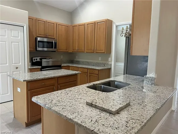 a kitchen with kitchen island granite countertop a sink a counter top space and cabinets