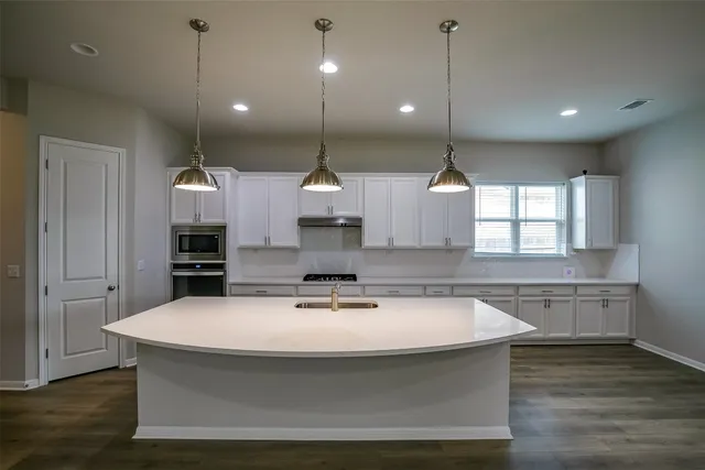 a kitchen with kitchen island a sink stainless steel appliances and wooden floor