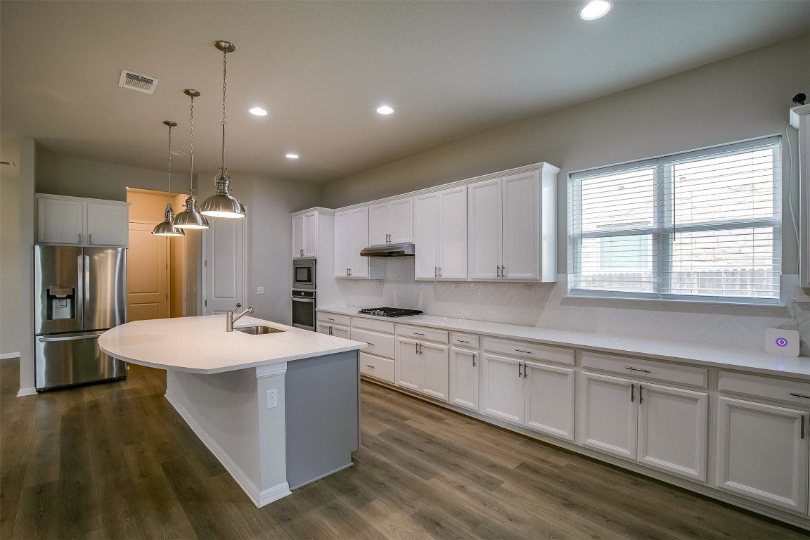 128 Ridgeview Court Georgetown, TX 78628 - Photo 7 of 22 a large kitchen with kitchen island a sink a center island stainless steel appliances and a window