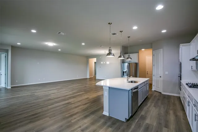 a open kitchen with kitchen island a sink dishwasher a stove and a refrigerator with wooden floor