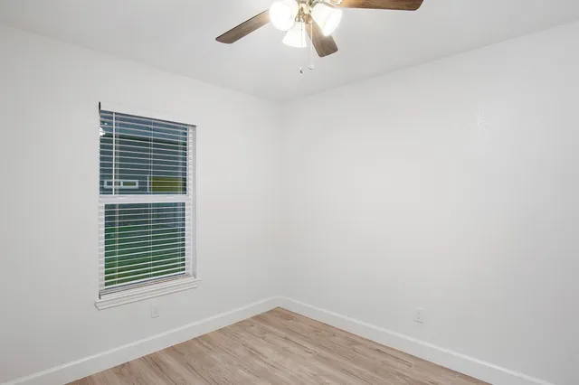 an empty room with wooden floor and ceiling fan