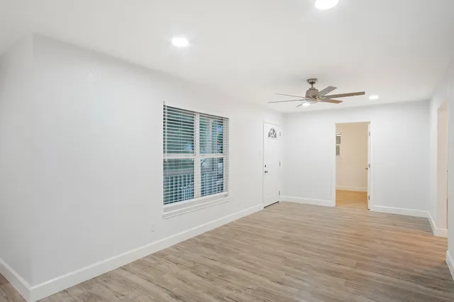 a view of an empty room with wooden floor and a window