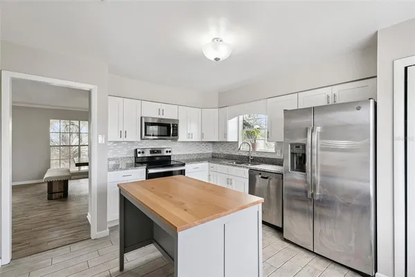 a kitchen with white cabinets appliances and a window