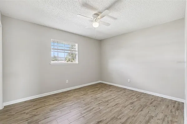 an empty room with wooden floor and a ceiling fan