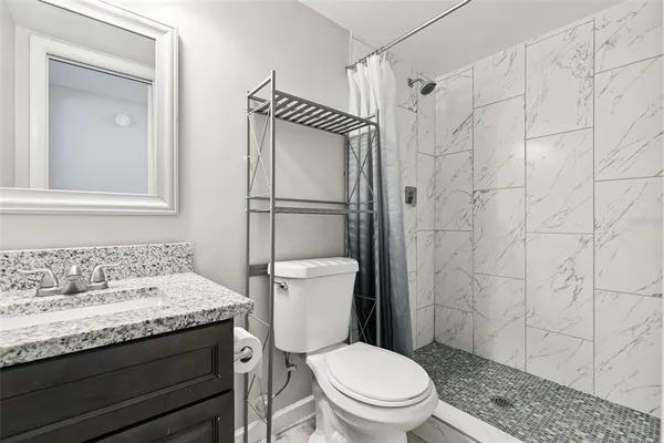 a bathroom with a granite countertop sink a toilet and a mirror