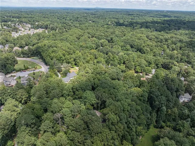 an aerial view of residential house with outdoor space and trees all around