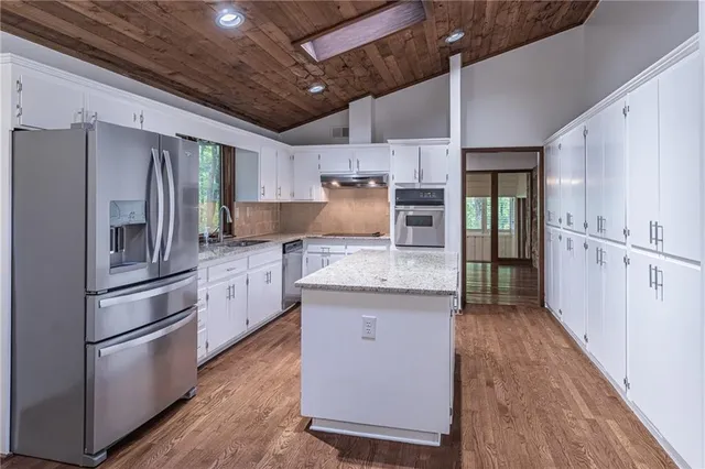 a kitchen with granite countertop a refrigerator and a stove top oven