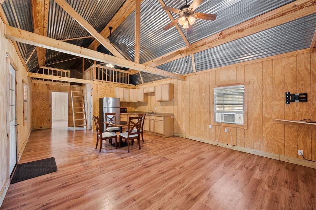 134 Maple Avenue Streetman, TX 75859 - Photo 11 of 19 Dining area featuring high vaulted ceiling, wood walls, light wood-style flooring, beamed ceiling, and ceiling fan