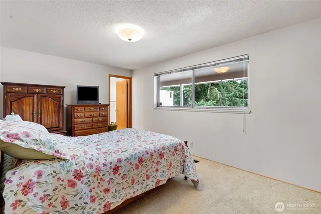 a bedroom with a bed and a flat tv screen on dresser