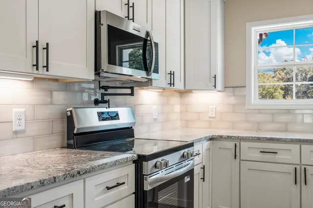 a kitchen with granite countertop a sink stainless steel appliances and cabinets