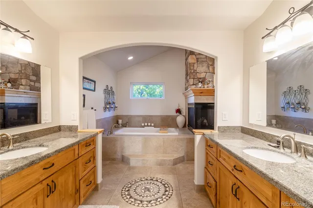 a large bathroom with a granite countertop double vanity sink a mirror and a bathtub
