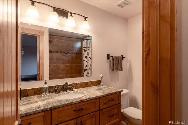 a bathroom with a granite countertop sink toilet and mirror