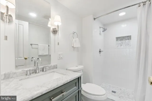 a bathroom with a granite countertop sink toilet a shower and a mirror