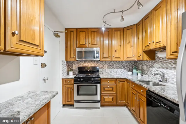 a kitchen with stainless steel appliances granite countertop white cabinets and window