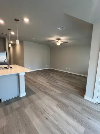 an empty room with wooden floor fan and window