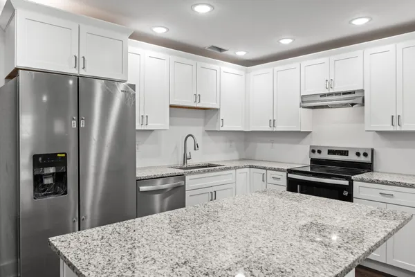 a kitchen with stainless steel appliances granite countertop a refrigerator sink and cabinets