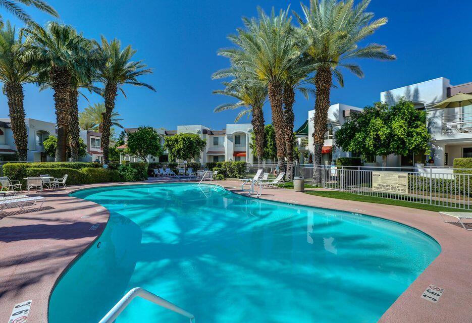 401 El Cielo Road, Unit 84 Palm Springs, CA 92262 - Photo 2 of 7 a view of a swimming pool with a lawn chairs and palm trees