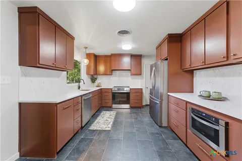a kitchen with stainless steel appliances granite countertop a refrigerator and a stove top oven